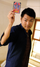 Miyake holding his character's tarot card